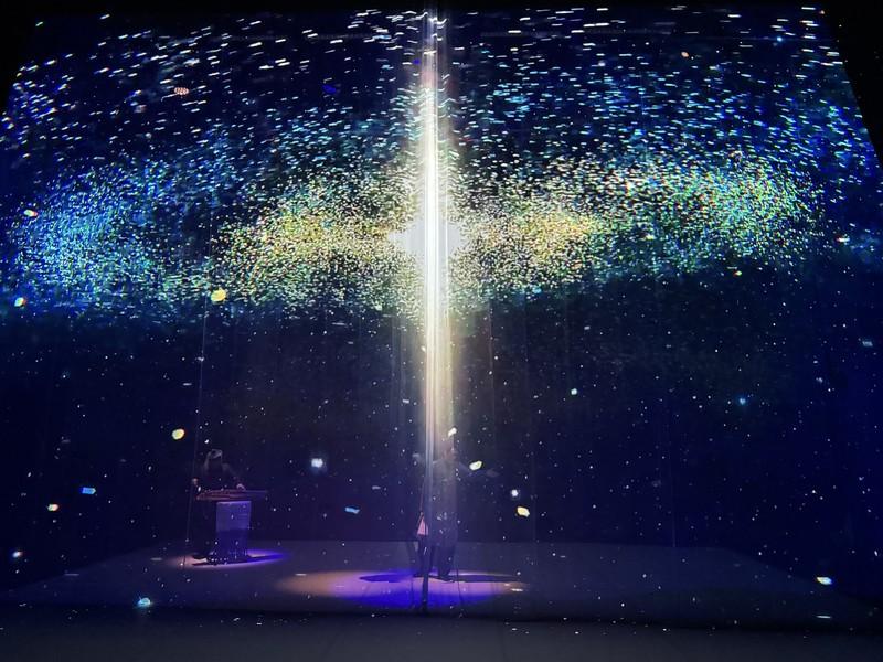 The climactic moment of the Dochebi XR Performance — a performer conducts a ritual within a pillar of light connecting heaven and earth