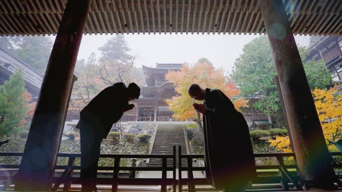 A moment of greeting as Lee Wook-jung and a Buddhist practitioner bow to each other with palms joined at a serene Japanese temple. Set against the deepening colors of autumn, the scene captures the journey of Kitchen of Buddha in search of food, spiritual practice, and the wisdom of life.